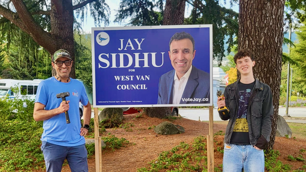 Jay Sidhu poses with a volunteer while putting up campaign signs