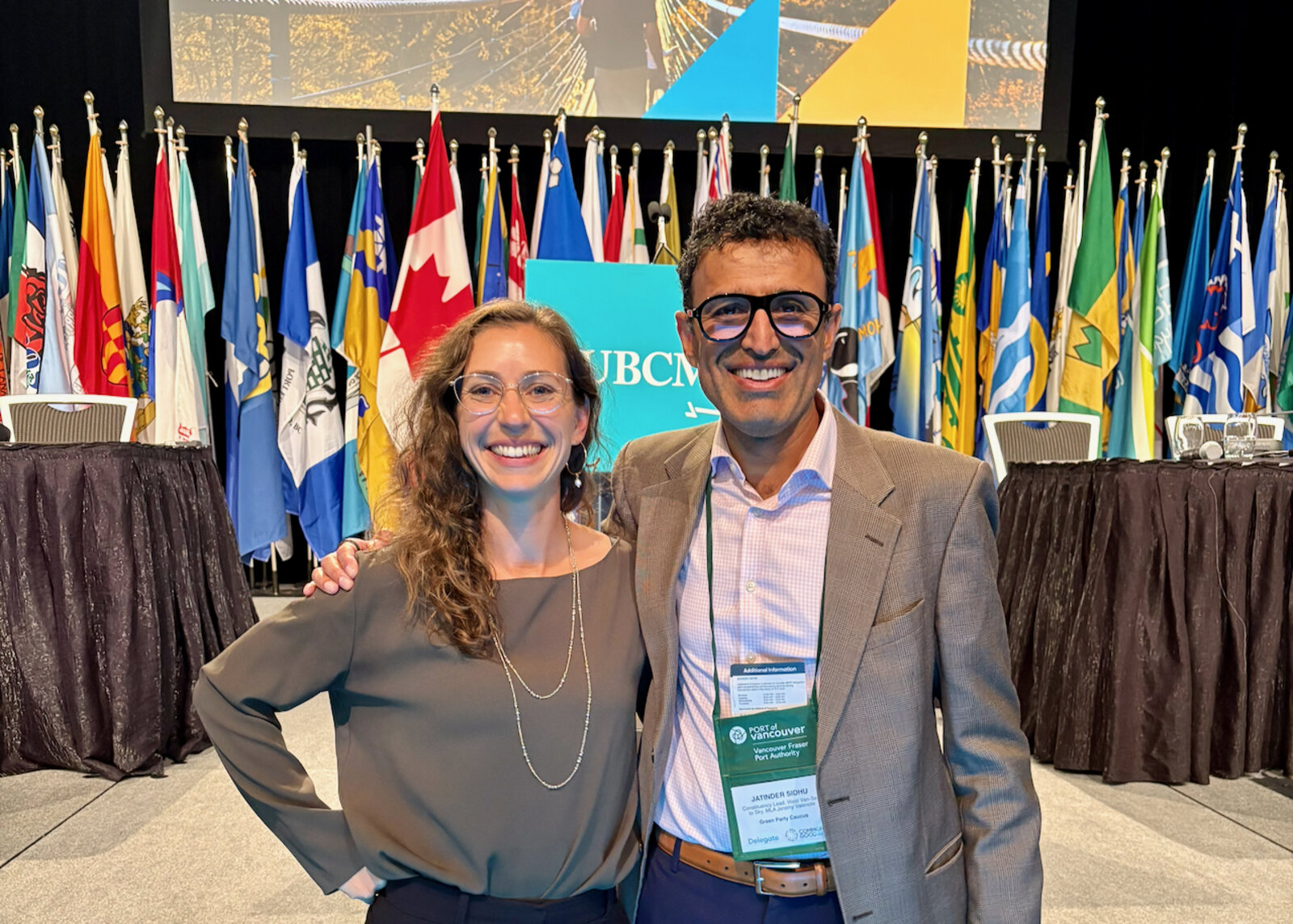 Jay Sidhu with a colleague at the UBCM conference, in front of municipal flags
