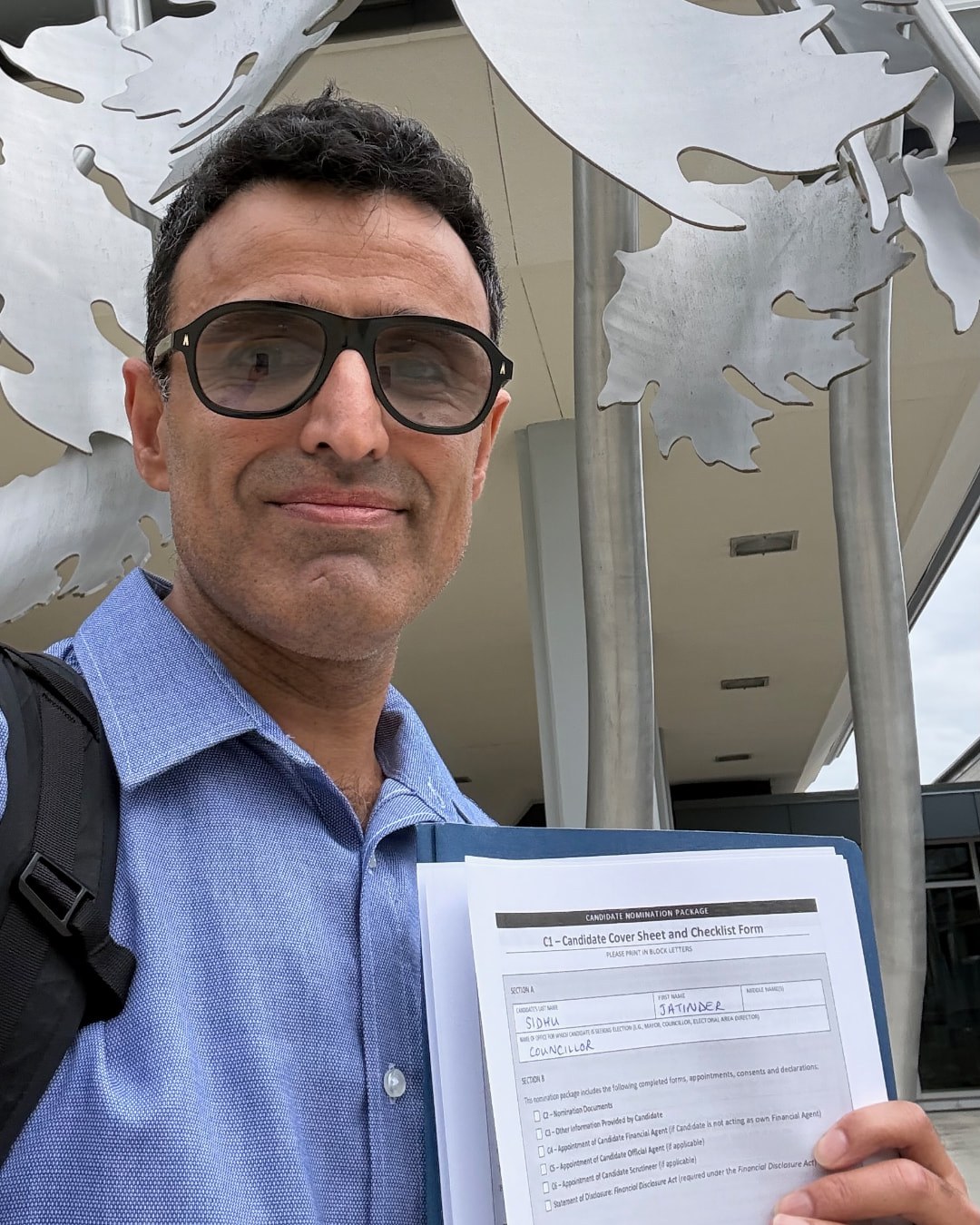 Jay Sidhu holding his candidate nomination package outside West Vancouver Municipal Hall